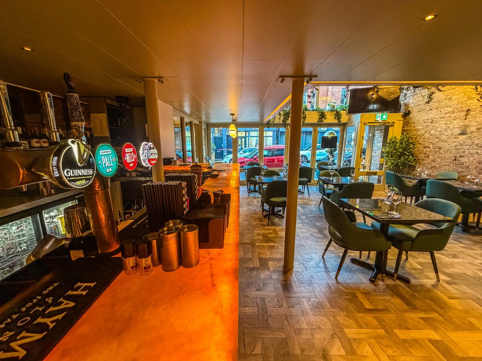 Teatro's ground-floor restaurant with green chairs, marble tables and hanging plants